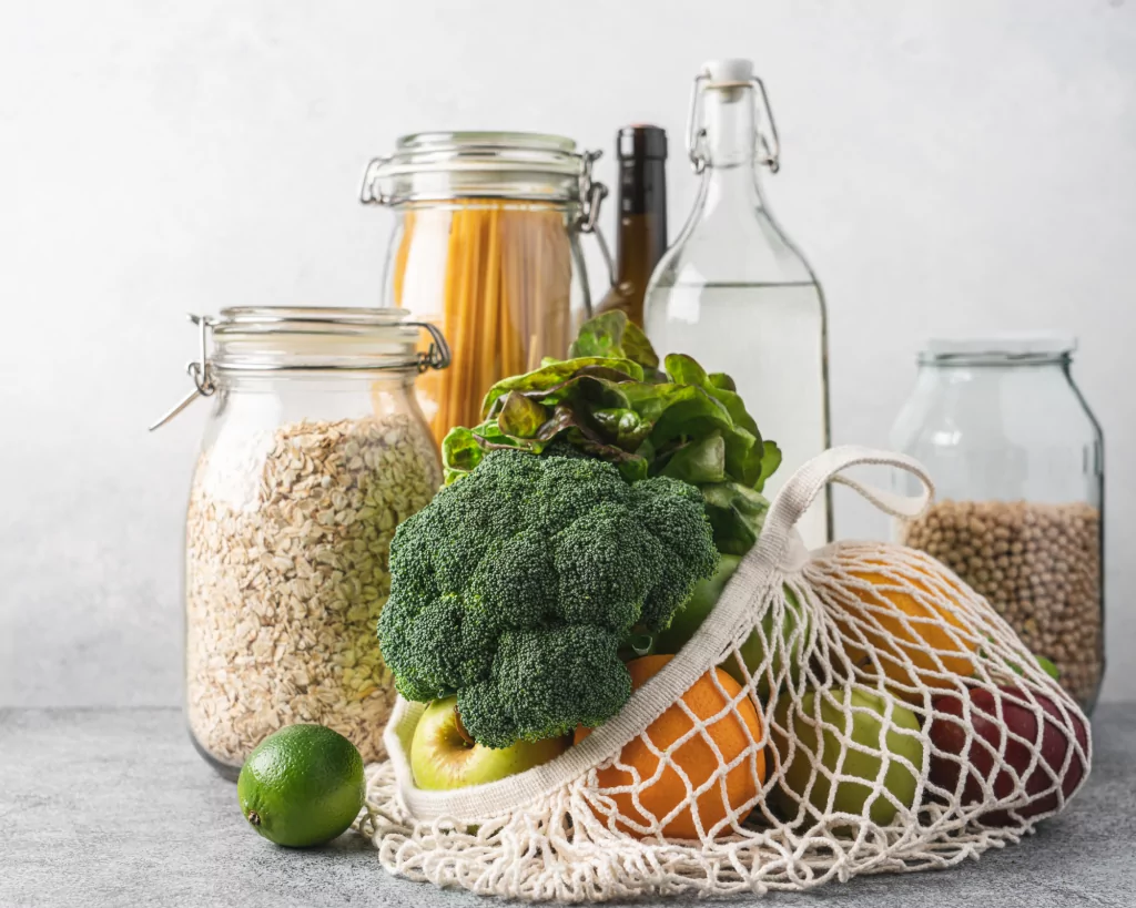 légumes dans un filet , des bocaux avec du riz et des pâtes regroupés sur une table